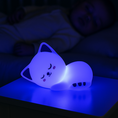 Bébé qui dort paisiblement grâce à la veilleuse chat posée sur la table de chevet qui diffuse une lumière bleue apaisante.